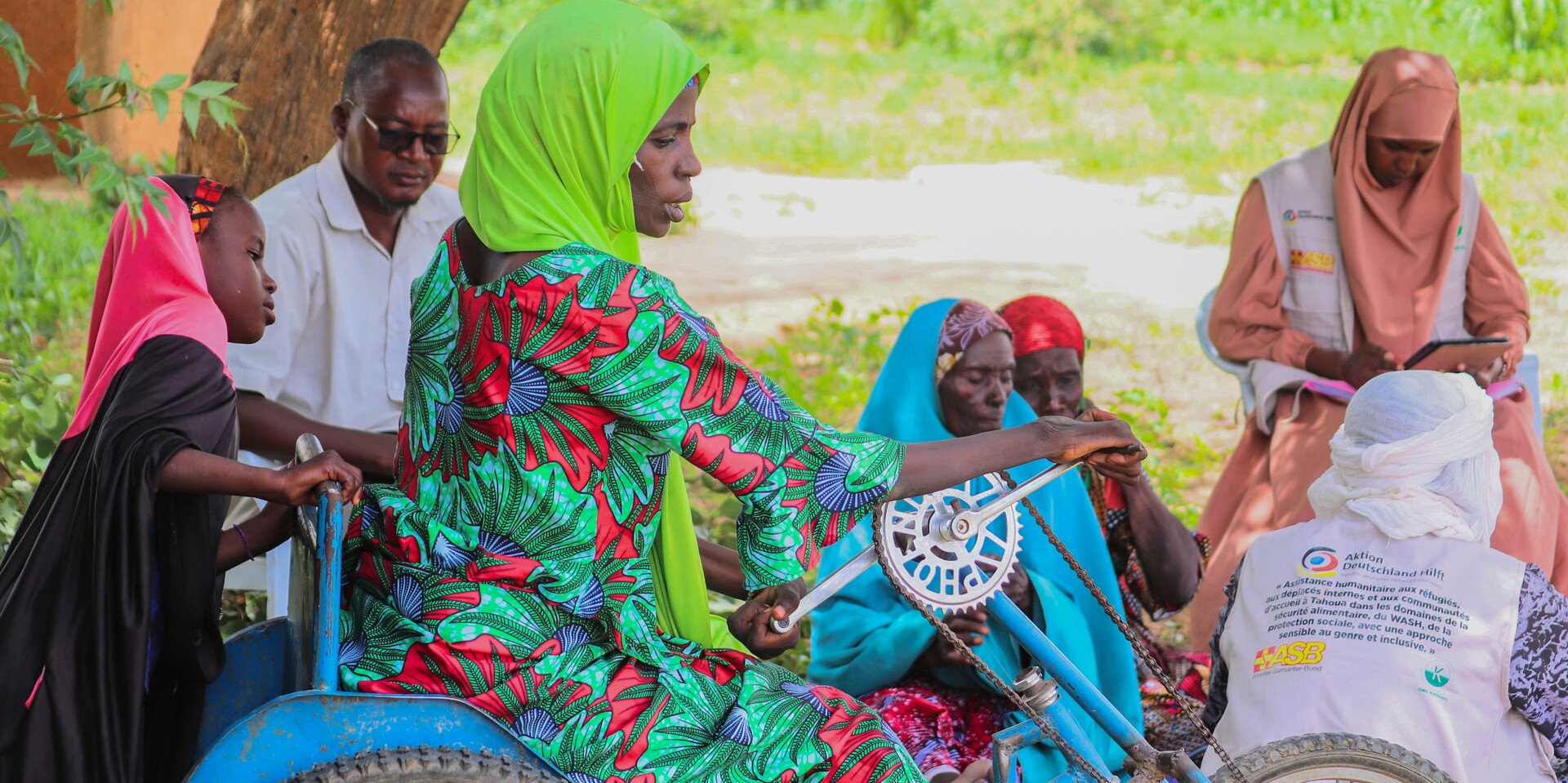 Eine Frau sitzt auf einem Fahrrad vor verschiedenen Menschen im Niger