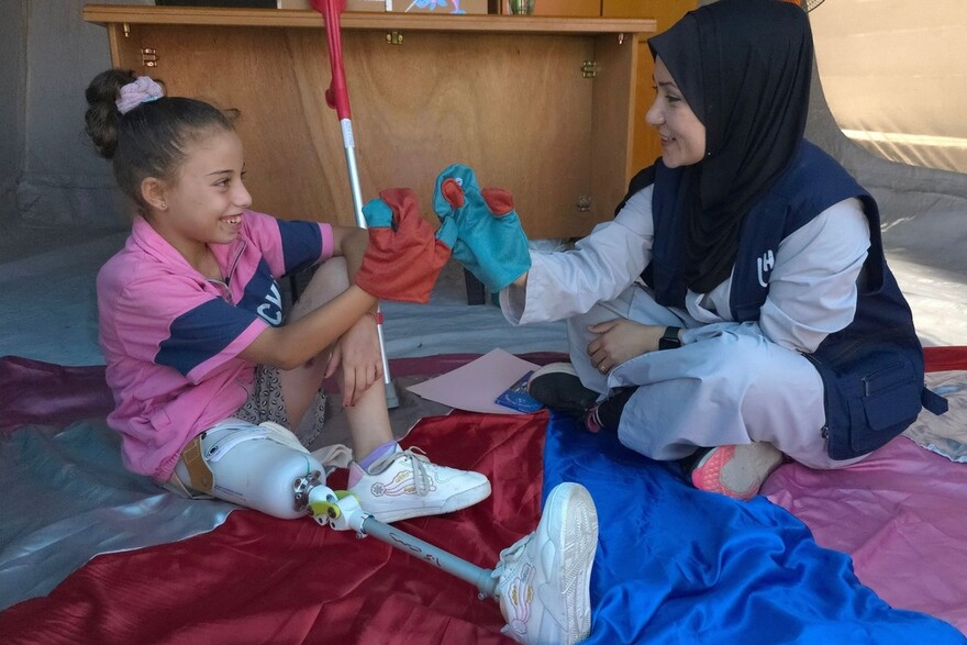 Eine Helferin von Hanicap International bietet einem Mädchen mit Prothese psychologische Unterstützung