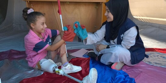 Eine Helferin und ein Kind mit einer Prothese reichen sich die Hände Eine Helferin und ein Kind mit einer Prothese reichen sich die Hände