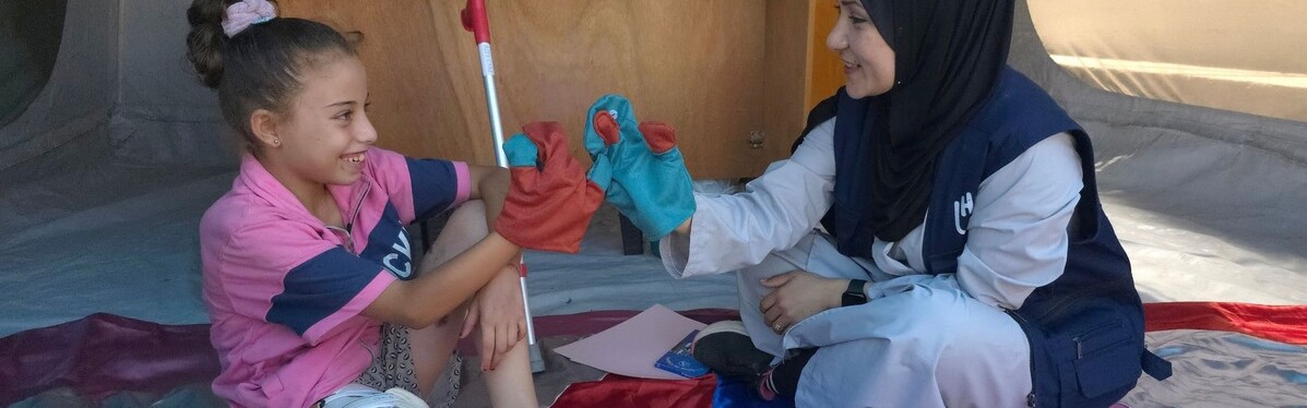 Eine Helferin und ein Kind mit einer Prothese reichen sich die Hände