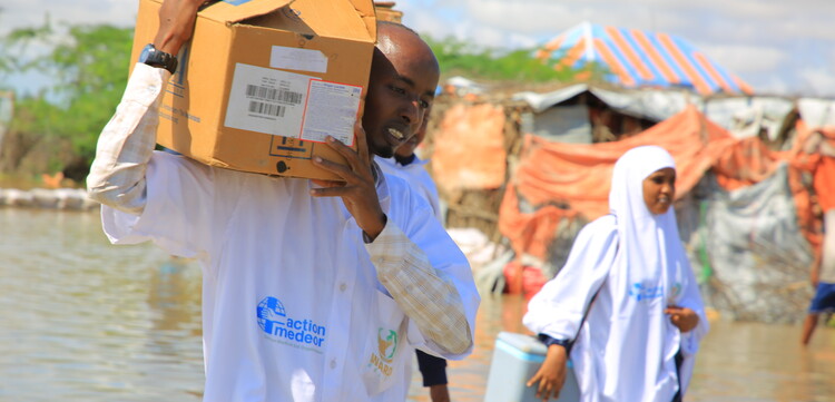 Helfer:innen von action medeor tragen in Somalia Pakete mit Hilfsgütern auf den Schultern