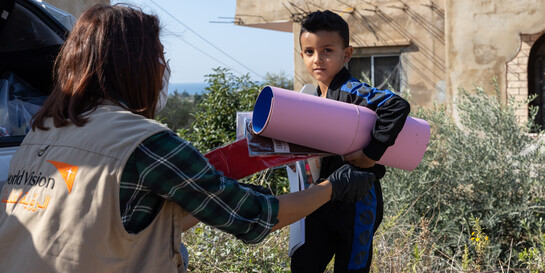 Eine Helferin von World Vision überreicht einem Kind im Libanon Spielsachen
