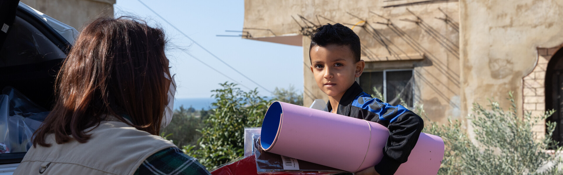 Eine Helferin von World Vision überreicht einem Kind im Libanon Spielsachen