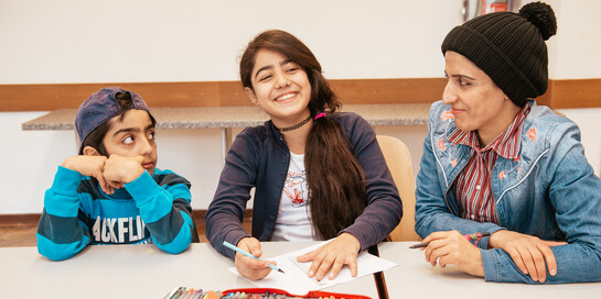 Mädchen und Junge lachen befreit während einer Therapie-Stunde.