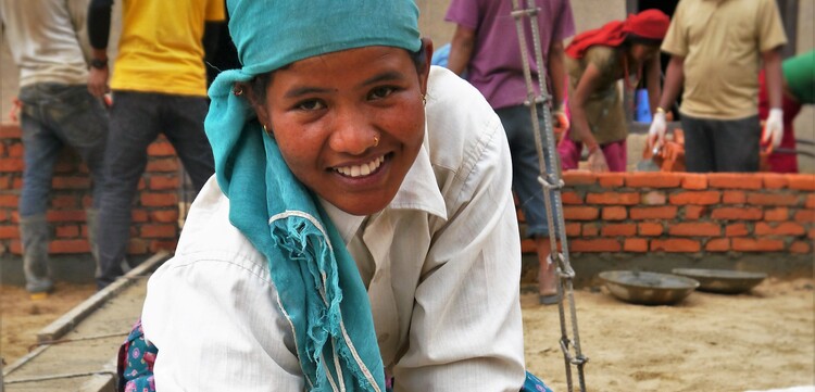 Eine Frau in Nepal hilft beim Bau erdbebensicherer Häuser
