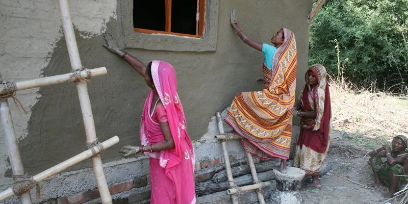 Frauen in Nepal verputzen ein Bambushaus