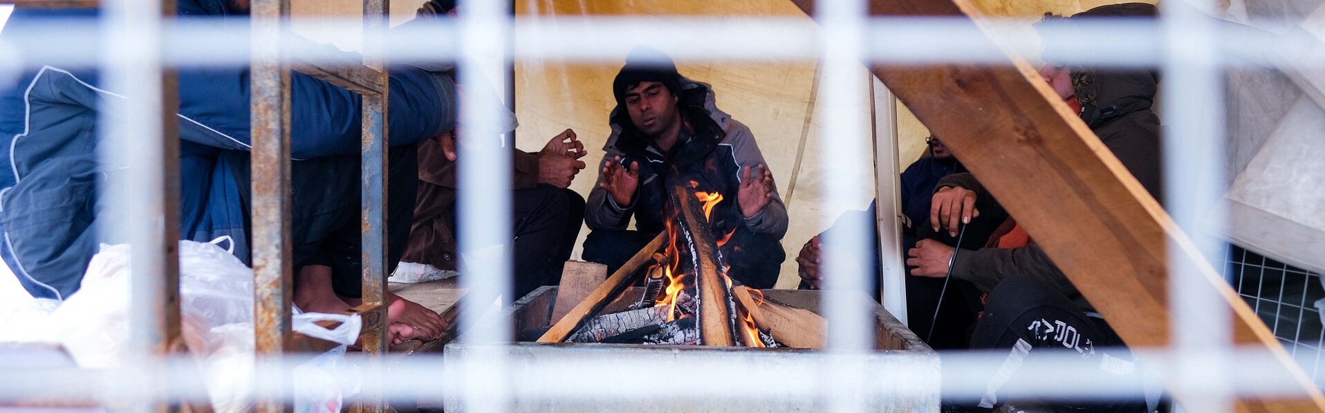 Flüchtlingslager Lipa: Flüchtlinge in einem Zelt wärmen sich an einem offenen Feuer, Copyright: Help - Hilfe zur Selbsthilfe/Bosnien