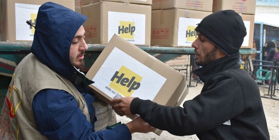 Zwei Helfer verladen Hilfspakete der Bonner Hilfsorganisation Help - Hilfe zur Selbsthilfe