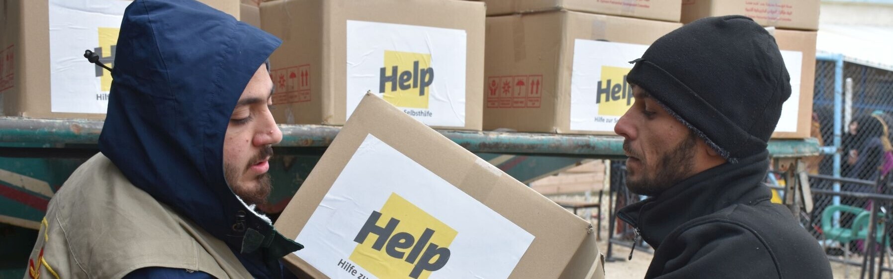 Zwei Helfer verladen Hilfspakete der Bonner Hilfsorganisation Help - Hilfe zur Selbsthilfe