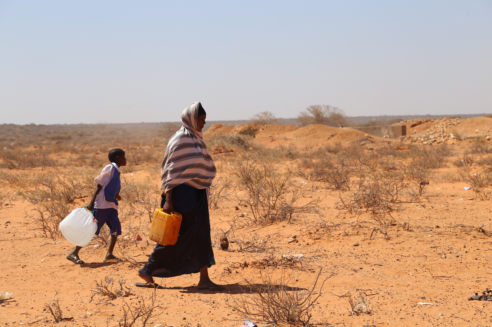 Eine Frau und ein Kind aus Afrika beim Wasserholen in der Wüste