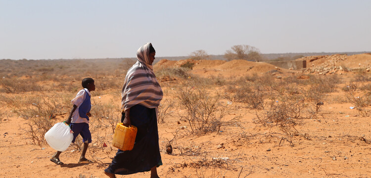 Eine Frau und ein Kind aus Afrika beim Wasserholen in der Wüste