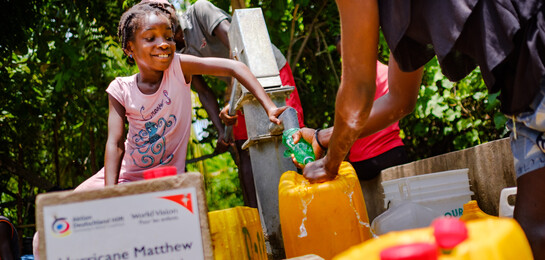 In Haiti holen ein Mädchen und seine Familie Wasser an einer Pumpe