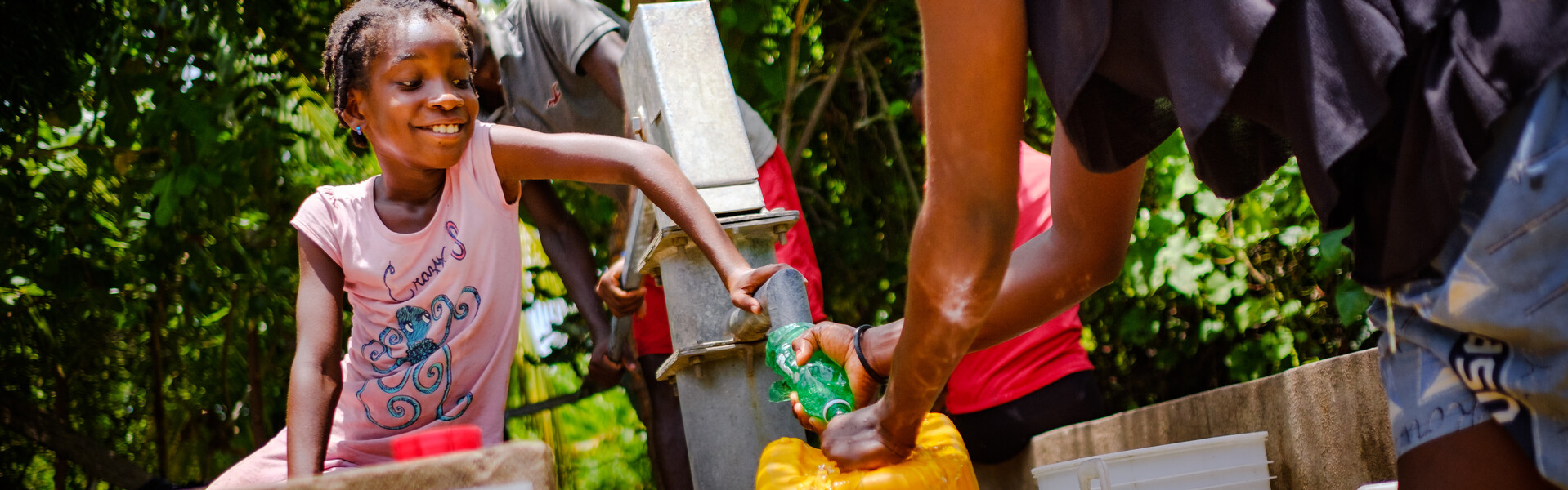 In Haiti holen ein Mädchen und seine Familie Wasser an einer Pumpe