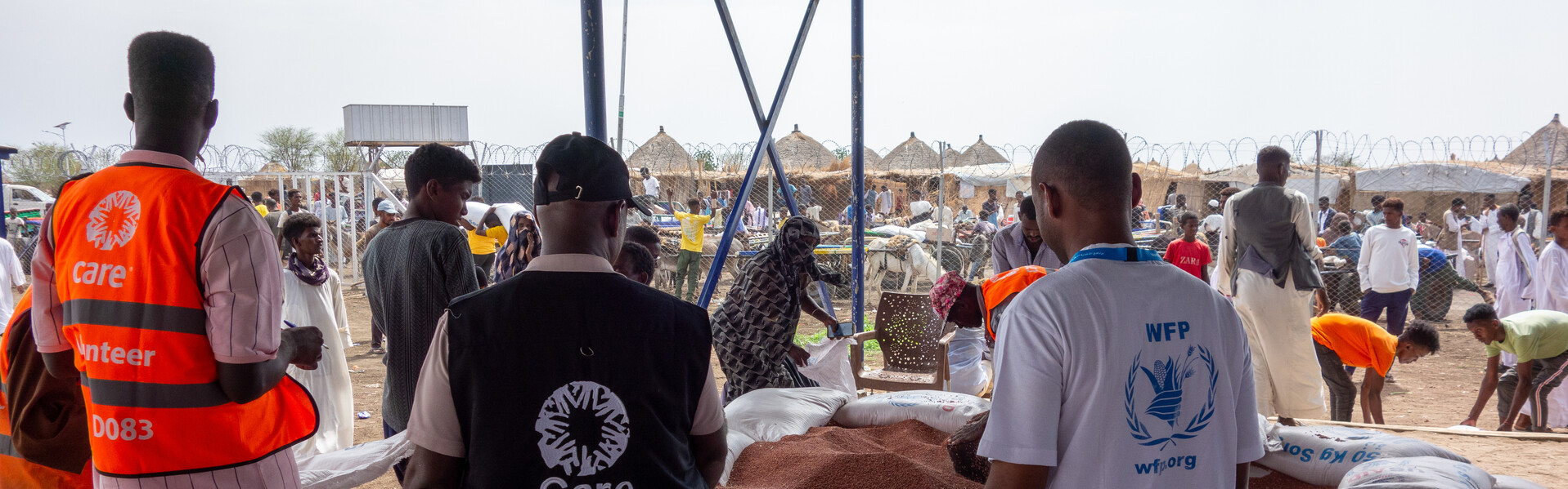 Drei Helfer:innen von CARE verteilen Lebensmittel an Vertriebene im Sudan 