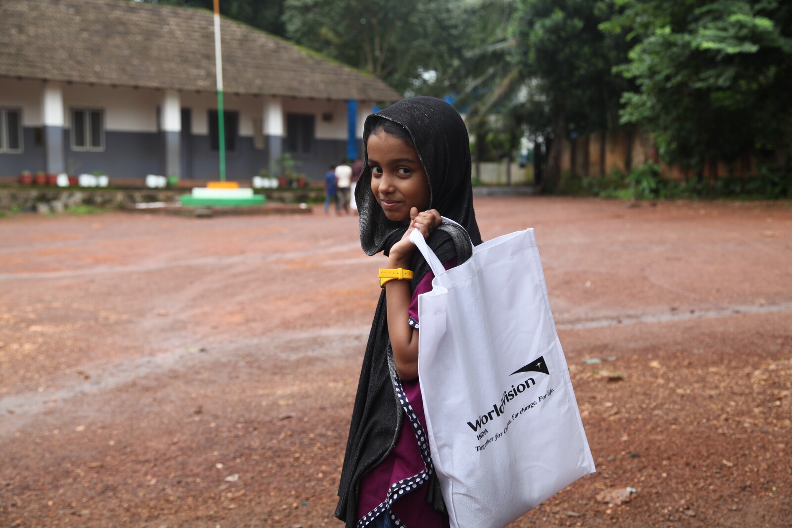 Ein indisches Mädchen trägt einen Jutebeutel von der Hilfsorganisation World Vision