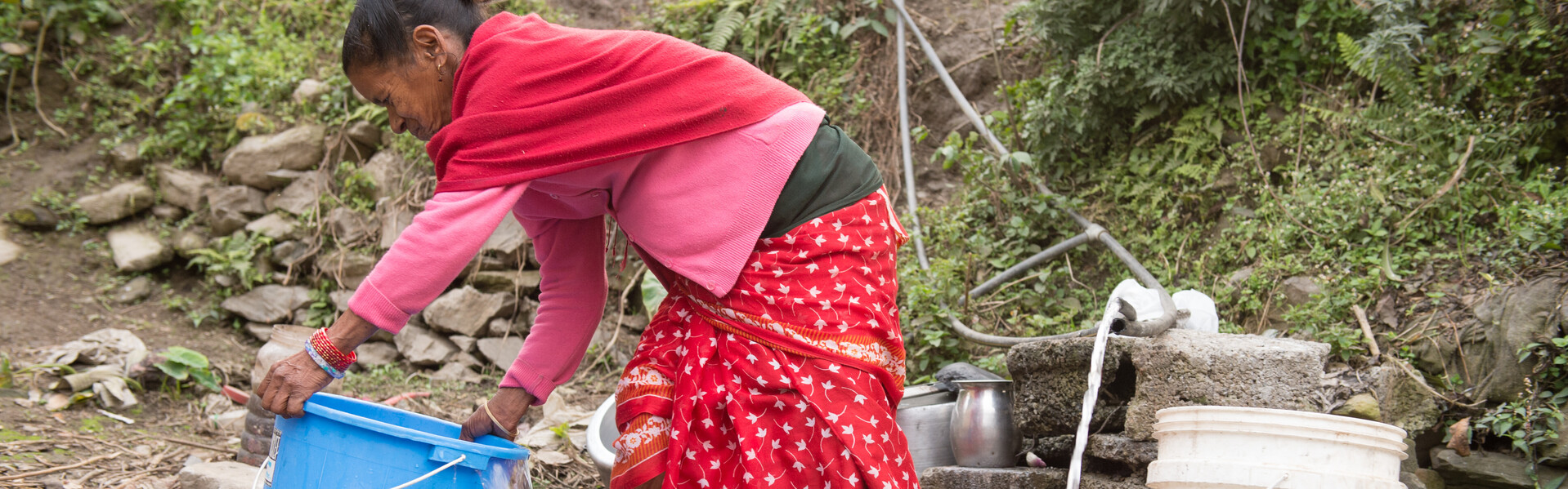 Nach dem schweren Erdbeben in Nepal vor einem Jahr werden Häuser wieder aufgebaut. Eine Frau holt sich sauberes Trinkwasser aus einem Brunnen.