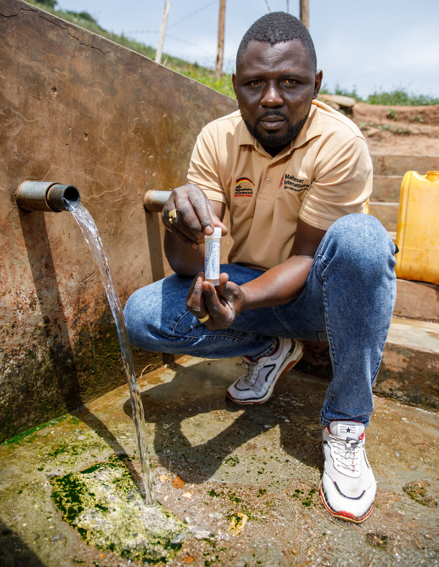 Ein Mann testet an einer Wasserquelle die Wasserqualität