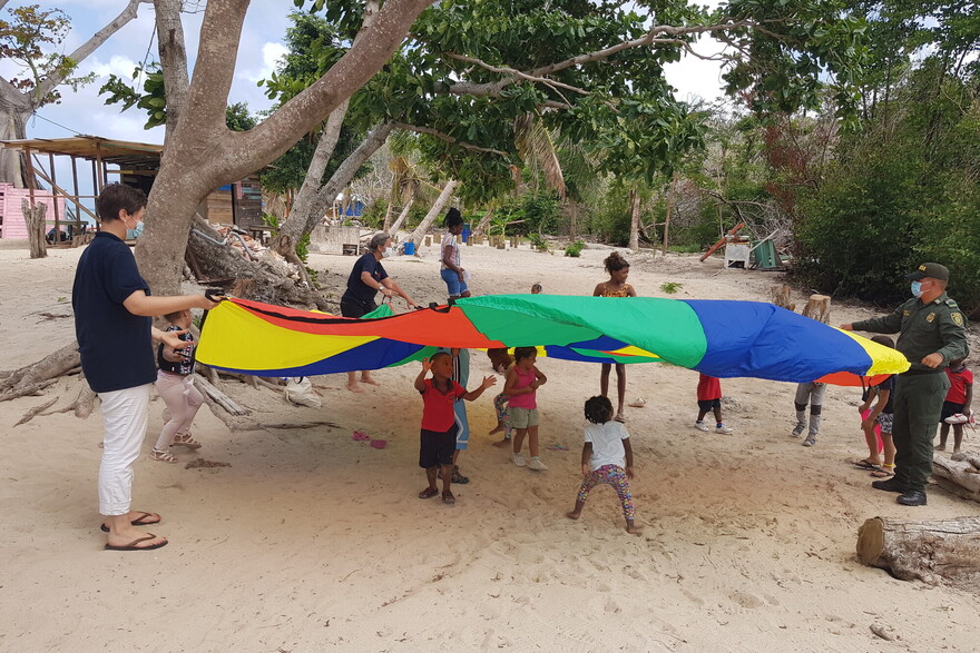 Viele Kinder spielen gemeinsam mit Helfer:innen und einem bunten Tuch in Kolumbien Viele Kinder spielen gemeinsam mit Helfer:innen und einem bunten Tuch in Kolumbien