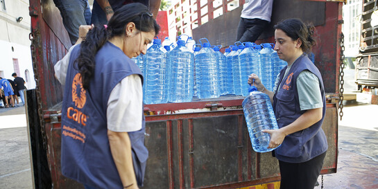 Zwei Helferinnen von CARE laden große Wasserbehälter aus einem Lastwagen aus