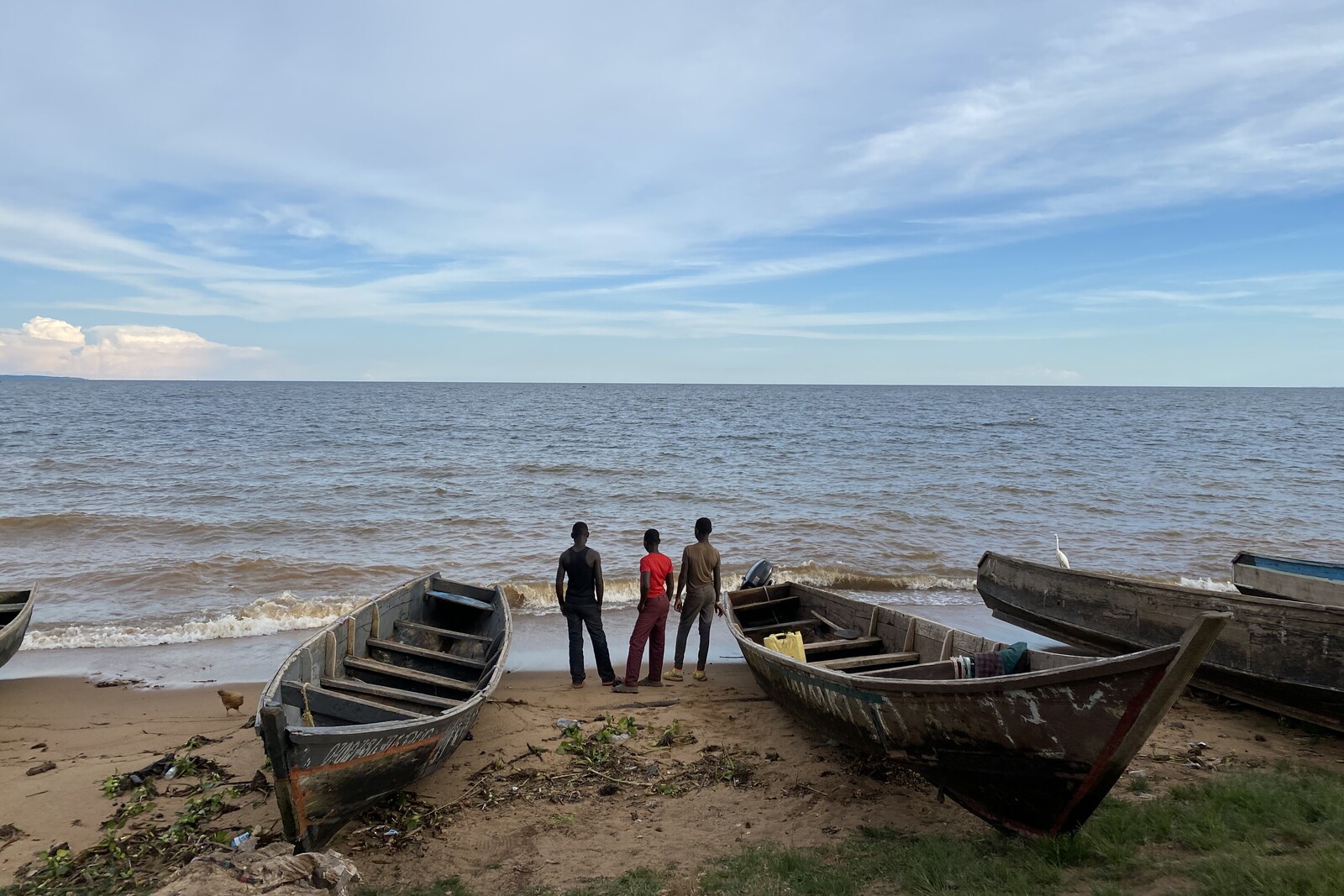 Drei Männer stehen neben ihren Booten am Viktoriasee in Uganda