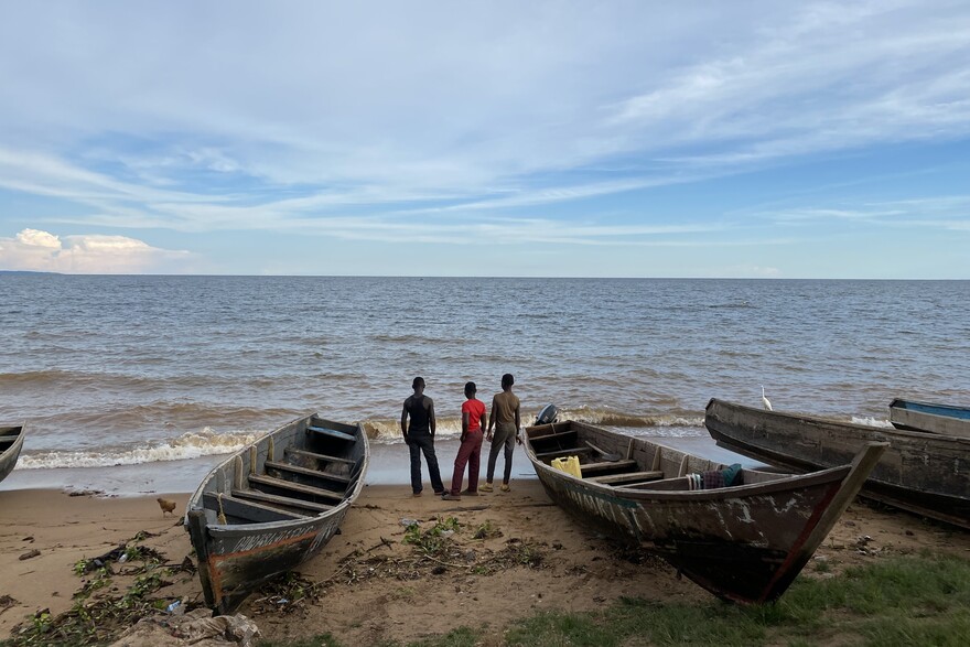 Drei Männer stehen neben ihren Booten am Viktoriasee in Uganda Drei Männer stehen neben ihren Booten am Viktoriasee in Uganda