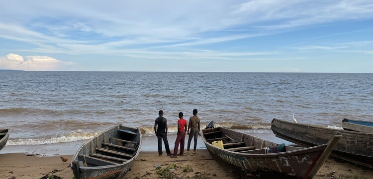 Drei Männer stehen neben ihren Booten am Viktoriasee in Uganda Drei Männer stehen neben ihren Booten am Viktoriasee in Uganda