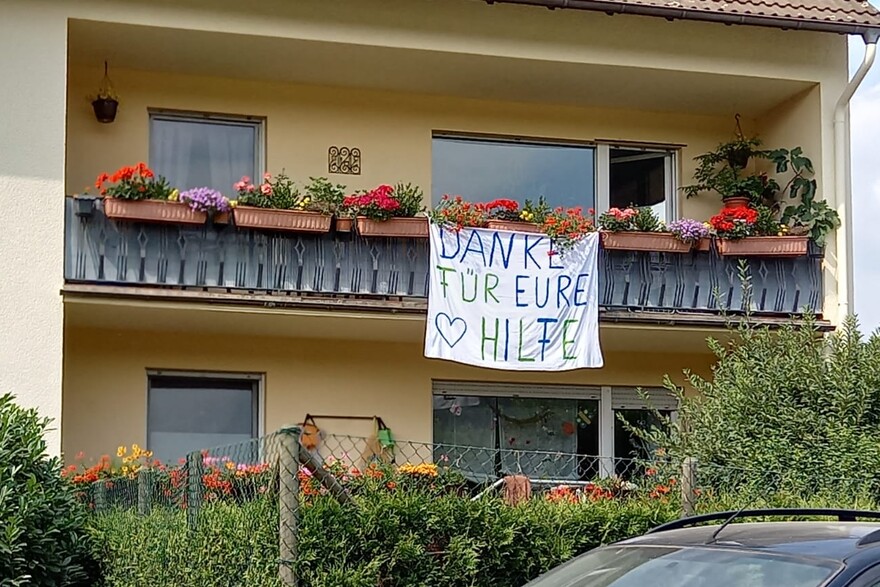 An einem Balkon hängt ein Banner mit der selbstgeschriebenen Aufschrift Danke für eure Hilfe