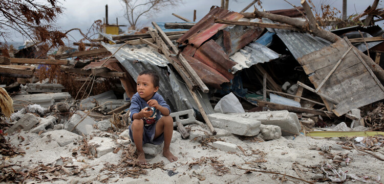 Nach dem Wirbelsturm: ein Kind vor zerstörten Häusern auf den Philippinen