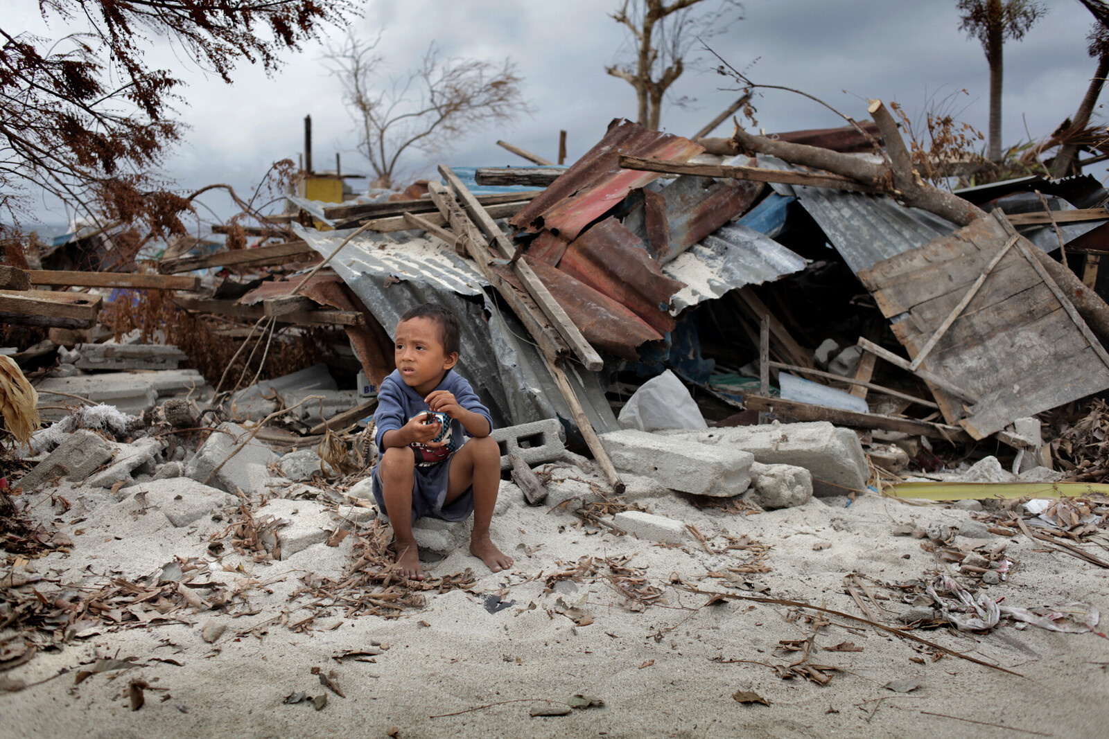 Nach dem Wirbelsturm: ein Kind vor zerstörten Häusern auf den Philippinen