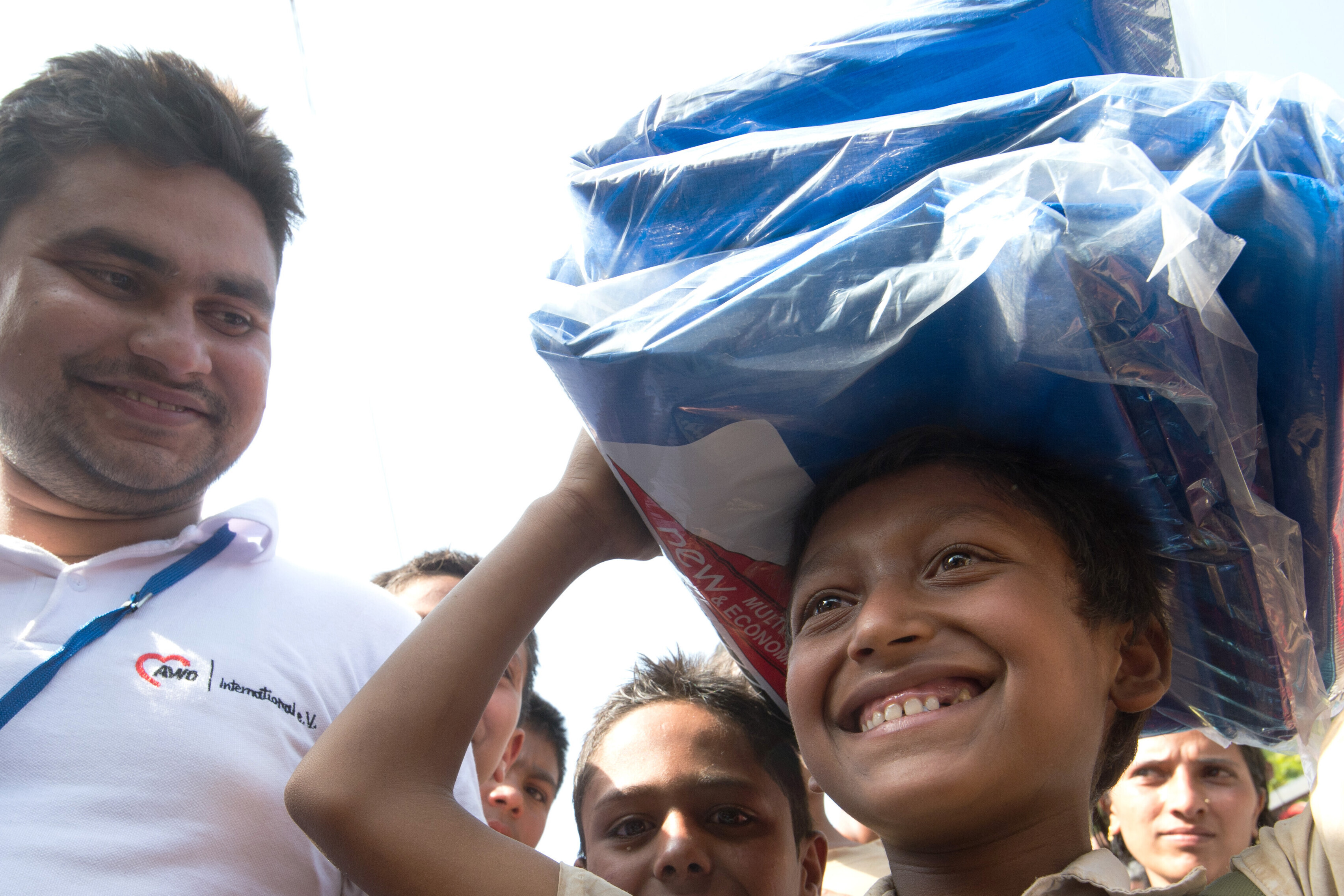 Junge in Nepal steht neben einem Humanitären Helfer