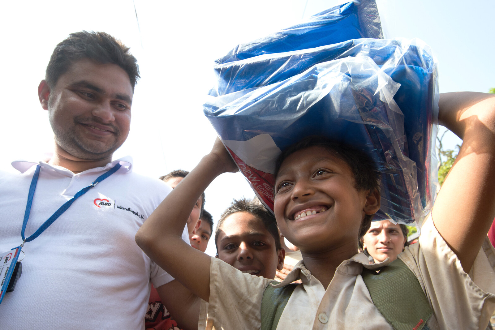 Junge in Nepal steht neben einem Humanitären Helfer