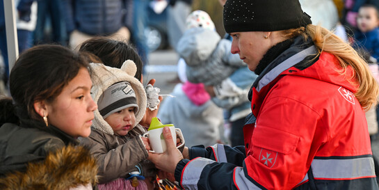 Eine Helferin von den ungarischen Maltesern versorgt geflüchtete Kinder aus der Ukraine  