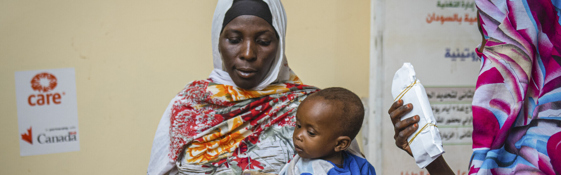 Eine Mutter im Sudan gemeinsam mit ihrem Kind, während sie finanzielle Nothilfe erhält