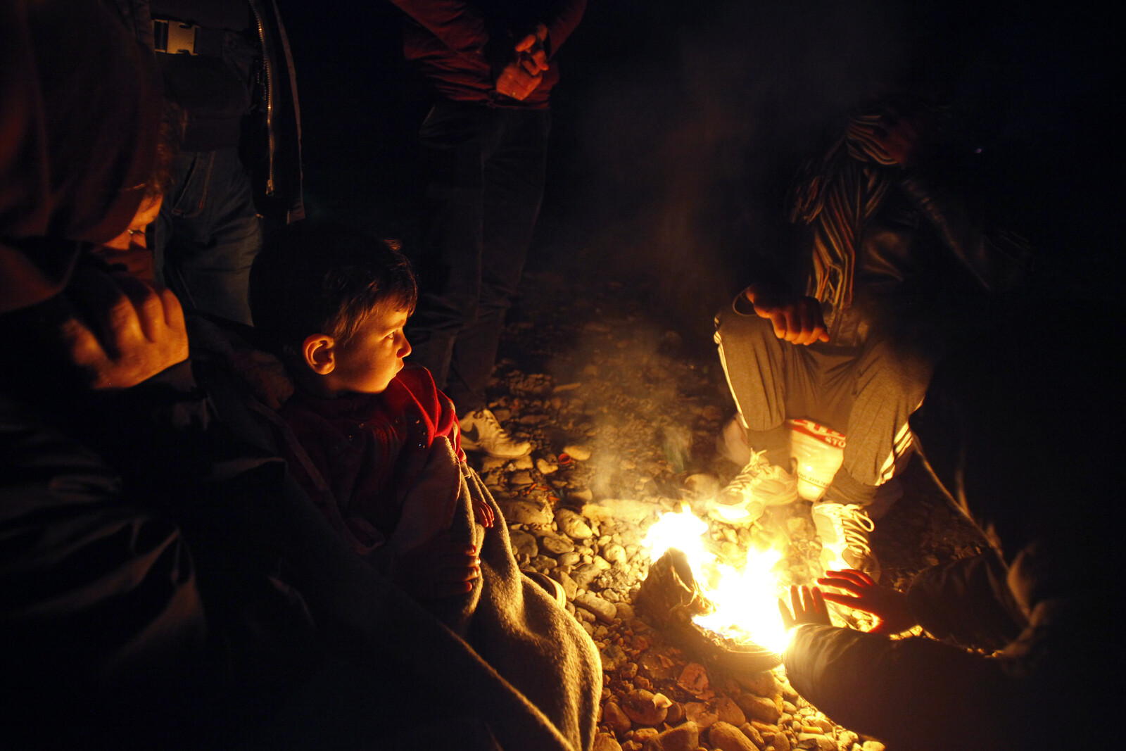 Menschen wärmen sich am Feuer