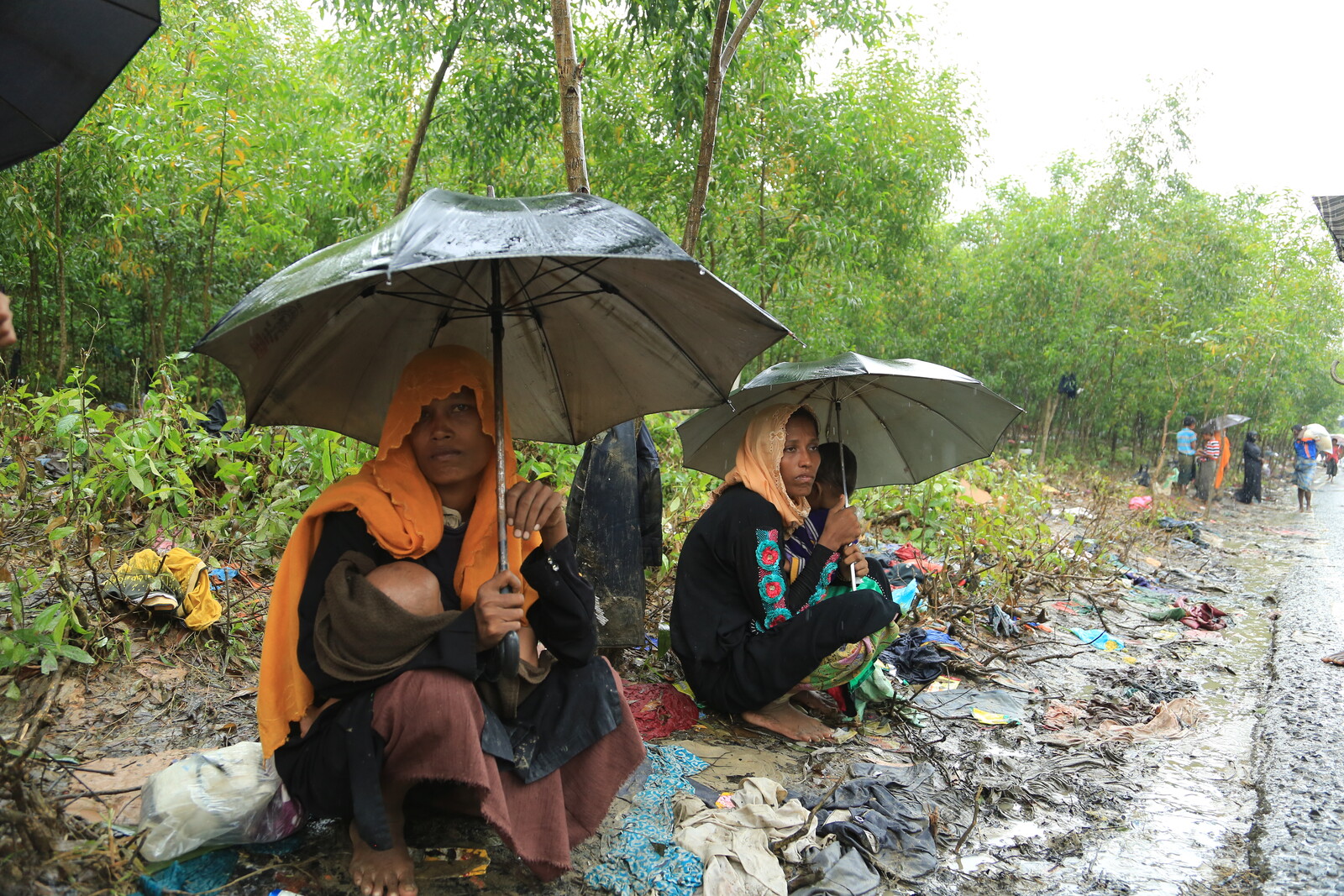 Frauen schützen sich und ihre Kinder mit Regenschirmen vor dem Regen