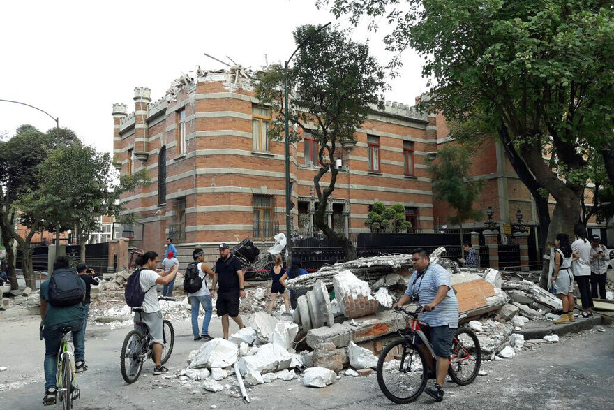In Mexiko verwüstete ein Erdbeben viele Häuser. Menschen stehen vor einer Häuserruine. In Mexiko verwüstete ein Erdbeben viele Häuser. Menschen stehen vor einer Häuserruine.