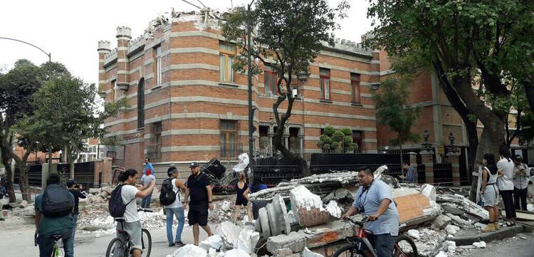 In Mexiko verwüstete ein Erdbeben viele Häuser. Menschen stehen vor einer Häuserruine.