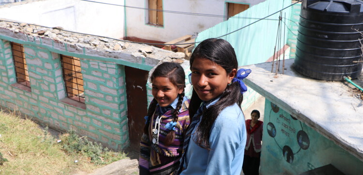 Zwei Mädchen stehen vor einer Baustelle in Nepal.