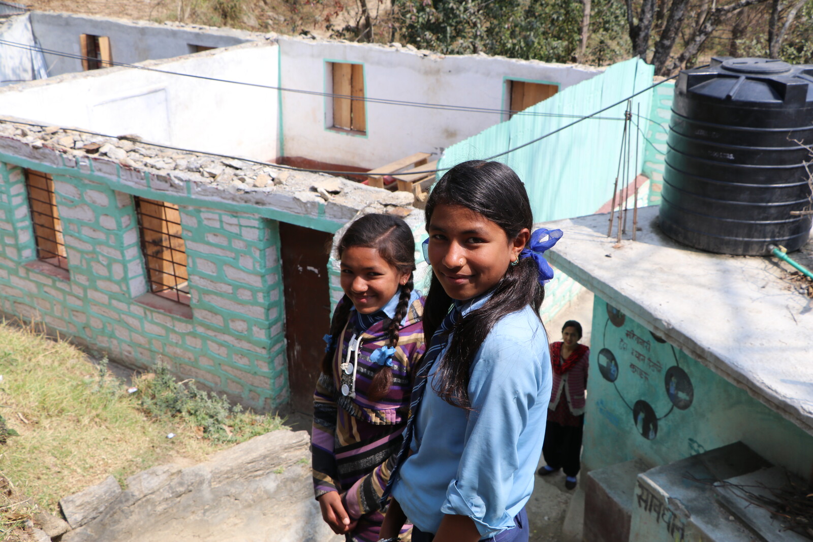 Zwei Mädchen stehen vor einer Baustelle in Nepal.