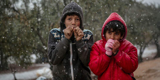 Zwei syrische Jungs in spärlicher Winterkleidung, die im Schnee frieren