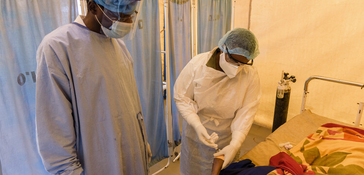 Ärzte mit Masken und Schutzanzügen legen bei einem Corona-Patienten in Tansania eine Infusion an