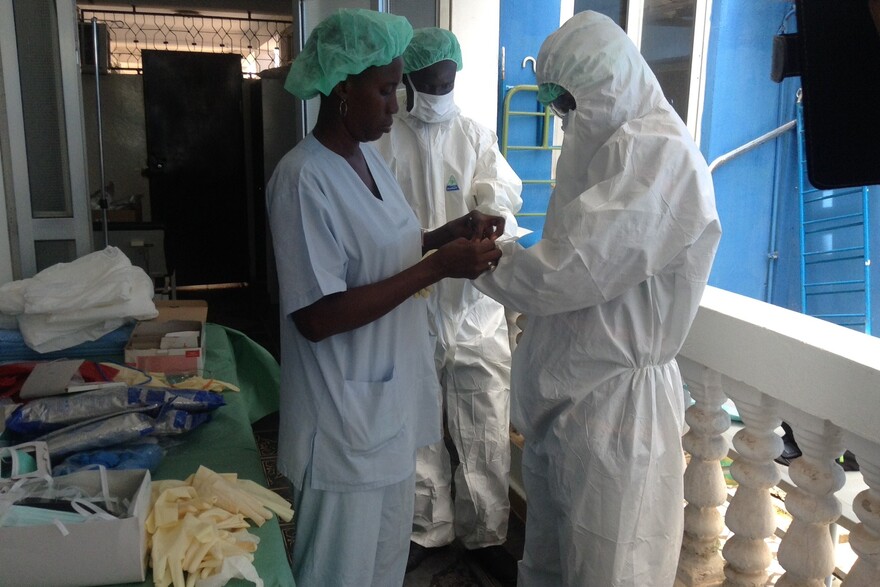 Helfer in Gambia ziehen sich Schutzkleidung an
