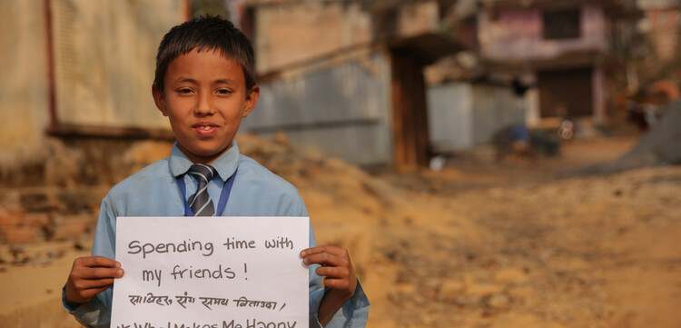 Ein Junge in Nepal ist glücklich über seine Familie.