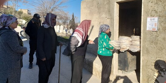 Mehrere Personen stehen in einer Schlange in Afrin, Syrien, um sich Brot abzuholen