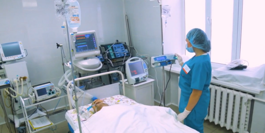 Eine maskierte Krankenschwester kümmert sich um einen Covid-19-Patienten, der an einem Atemgerät angeschlossen ist