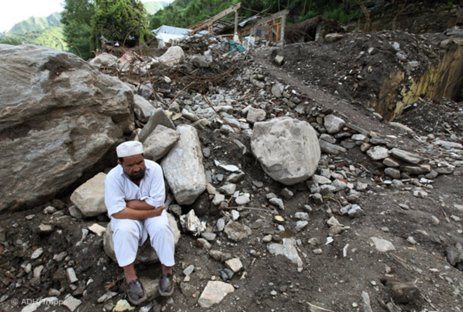 Flut Pakistan: Mann sitzt auf Bergen von Schutt