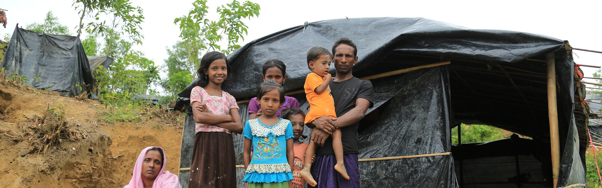 Eine geflüchtete Rohingya- Familie steht vor ihrer behelfsmäßigen Notunterkunft in Bangladesch