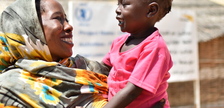 Eine Mutter aus dem Sudan hält glücklich ihr Kind im Arm
