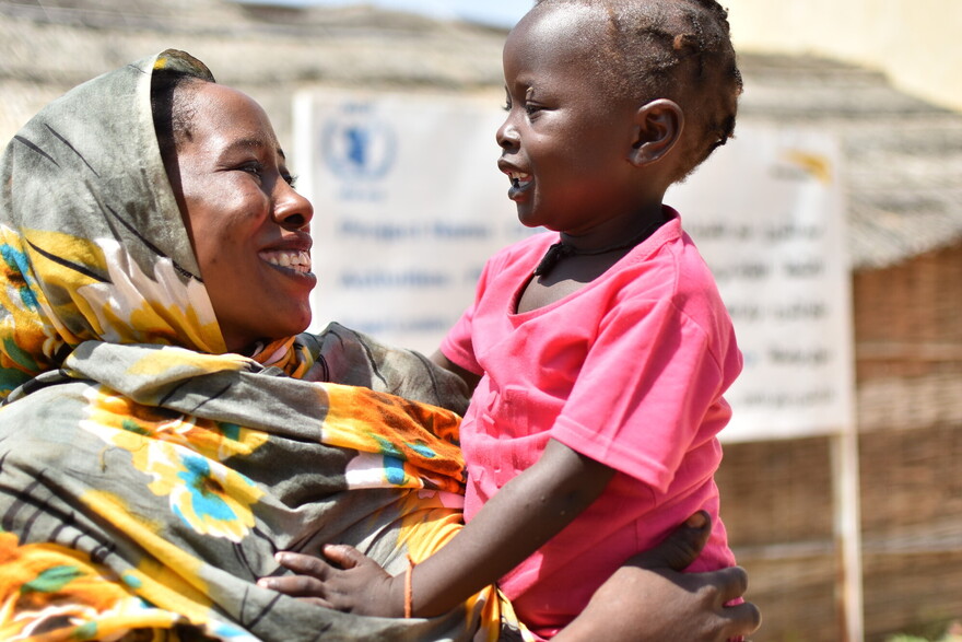 Eine Mutter aus dem Sudan hält glücklich ihr Kind im Arm Eine Mutter aus dem Sudan hält glücklich ihr Kind im Arm
