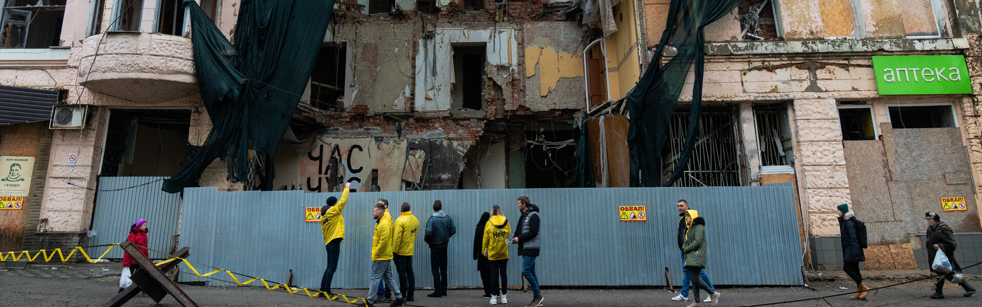 Menschen stehen in der Ukraine in Charkiw vor einem beschädigten Haus